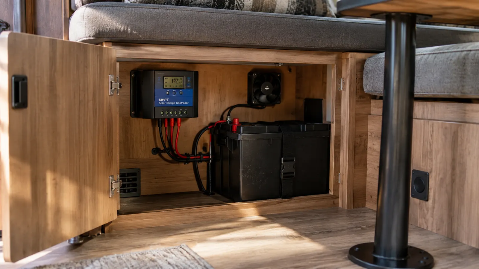 A solar charge controller mounted inside a travel trailer cabinet beside a battery box